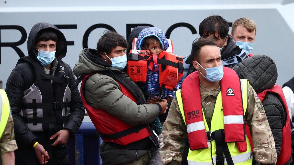 Migrants are escorted in Dover Harbour by military personnel after being rescued while crossing the English Channel on 1 May 2022