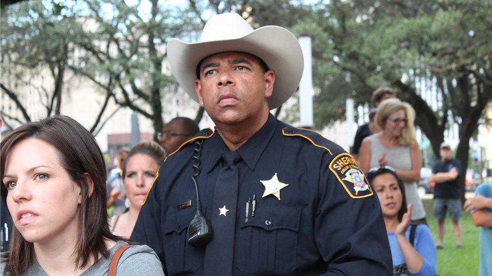 A sheriff's deputy listens to speakers at a memorial for the five slain officers