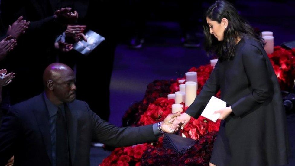 Former basketball player Michael Jordan helps Vanessa Bryant get off the stage during a public memorial for her late husband