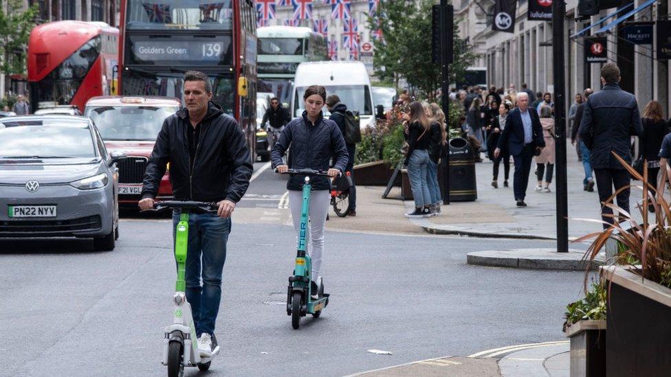 Man and woman riding e-scooter in central London