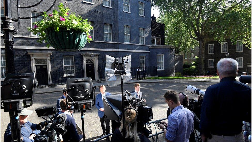 Members of the media wait outside of Downing Street