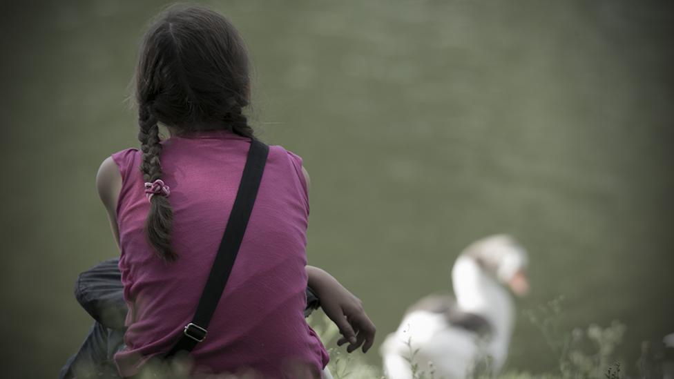 Girl sitting in nature, seen from behind