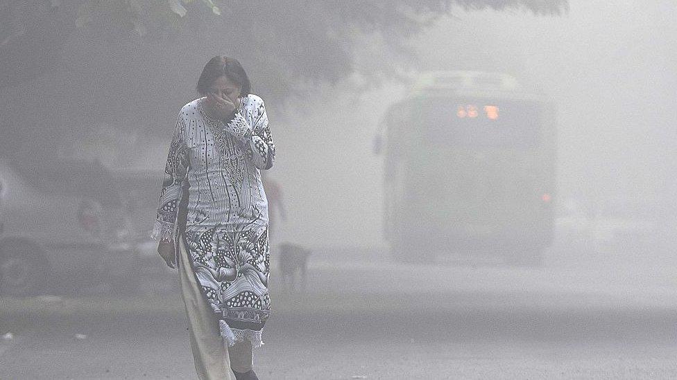 A women covers her face with her hands as she walks amid heavy smog in the early morning at Mayur Vihar area, on November 2, 2016 in New Delhi, India.