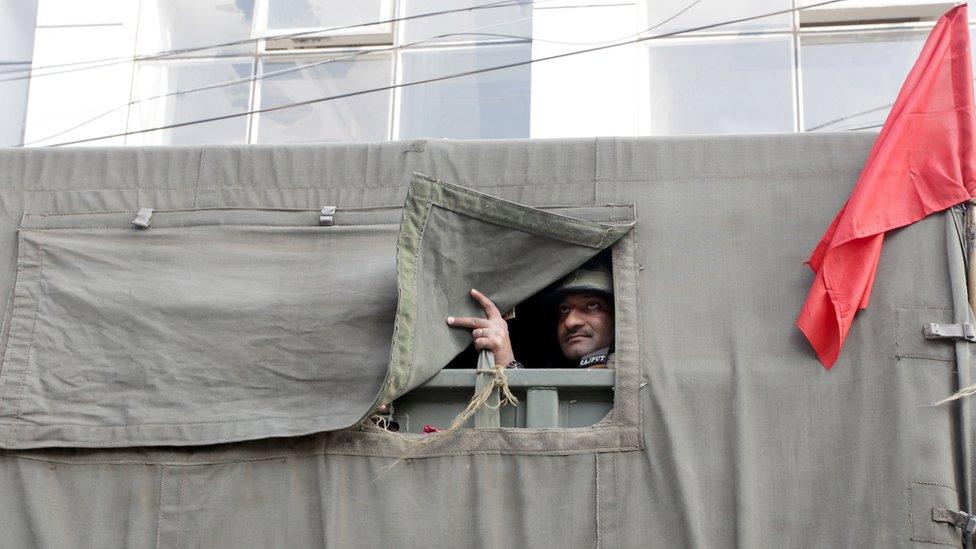 An Indian army soldier looks from the vehicle as they carry out a flag march during curfew in Jammu