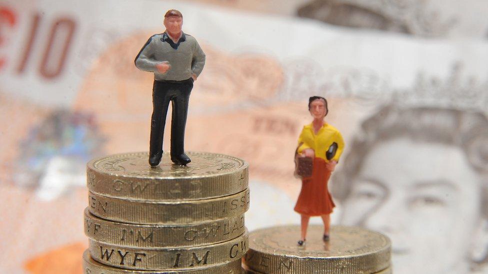 Man and woman stand on piles of coins