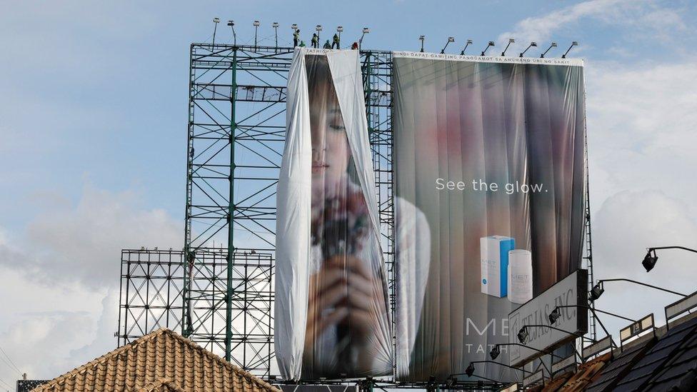 Workers roll advertising billboards along main road EDSA in preparation for the coming of Super Typhoon Mangkhut before it hits the main island of Luzon, in Quezon City