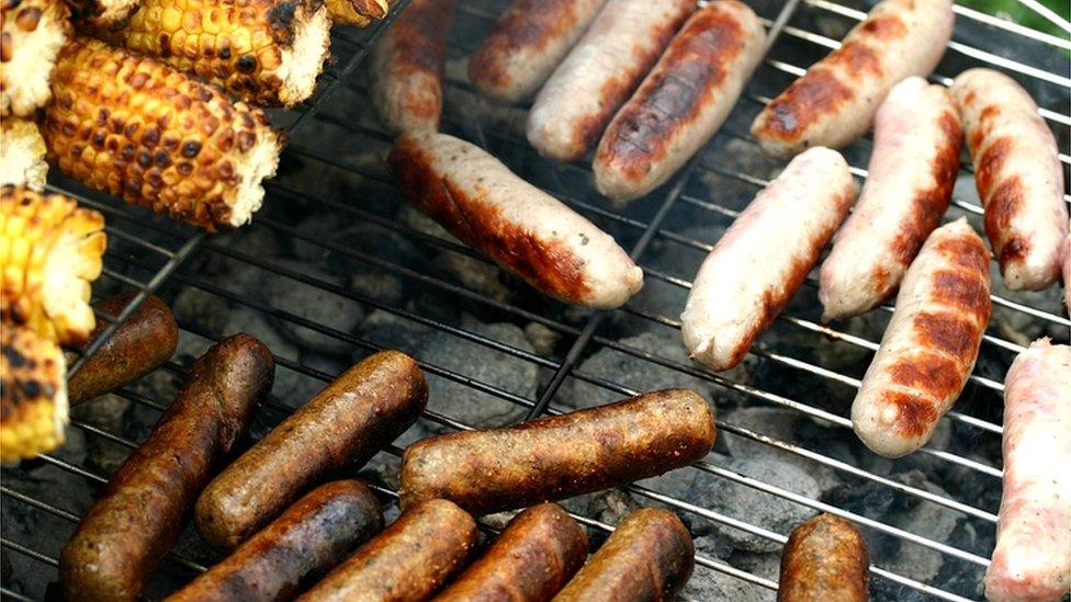 Sausages on the barbecue with vegetarian sausages at the bottom and meat sausages at the top of the picture