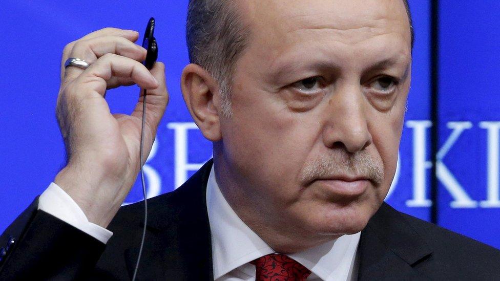 Turkish President Tayyip Erdogan removes his ear piece