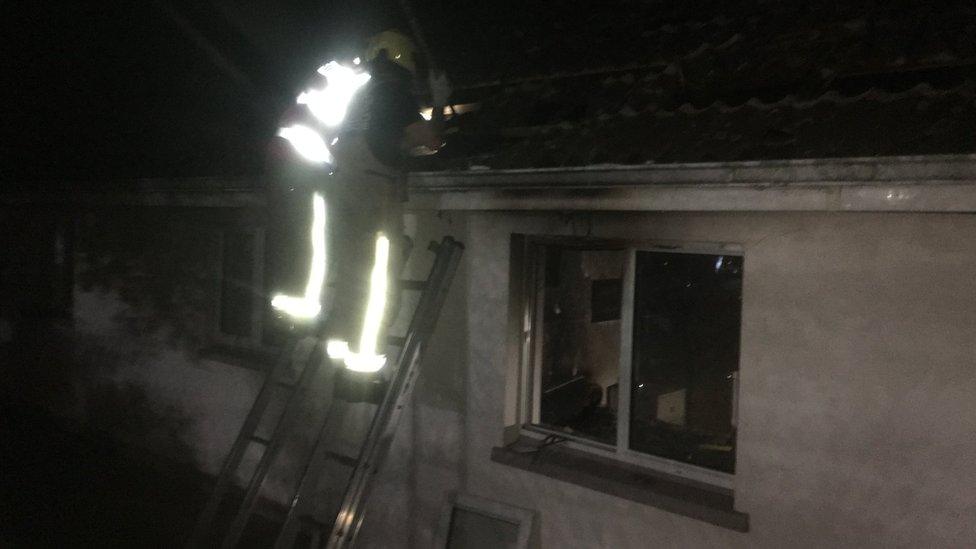 Firefighters on a roof in the dark