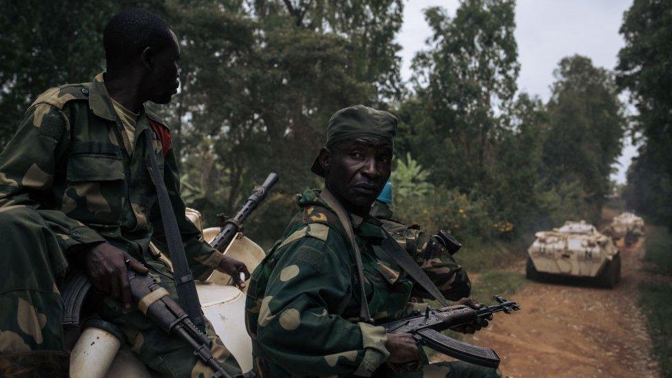 Congolese soldiers sitting on an armoured vehicle