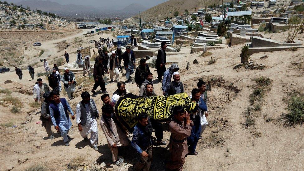 Afghan men carry the coffin of one of the victims of a suicide attack during a burial ceremony in Kabul, Afghanistan 25 July 2017