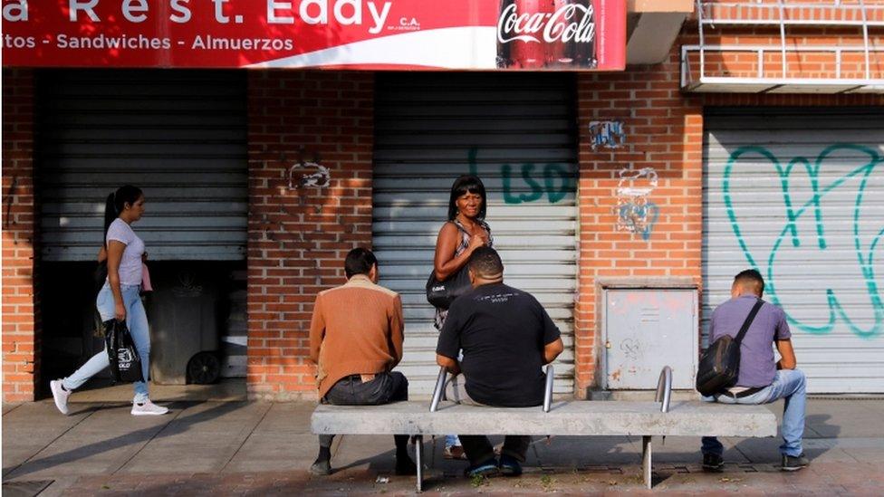 People gather outside boarded up shops