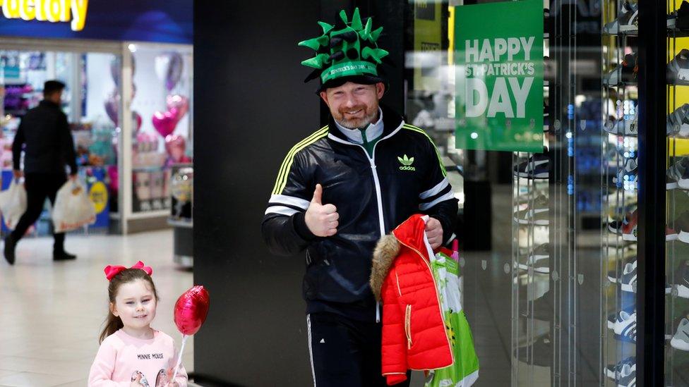 A man and child walking past a St Patrick's day sign in the Kennedy Centre in Belfast