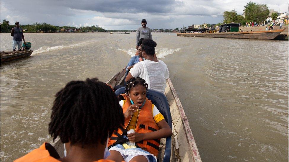 A group travels on the Atrato river in wooden canoes