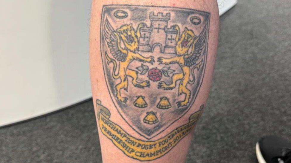 Tattoo of a crest with two lions, a castle entrance and a red rose