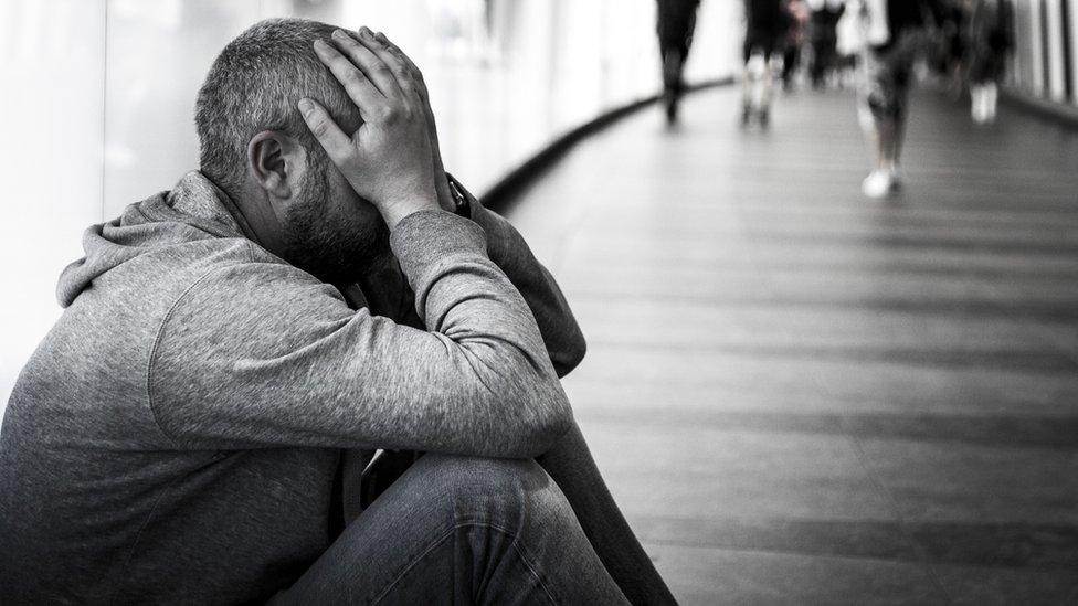 A man sitting outside with his head in his hands