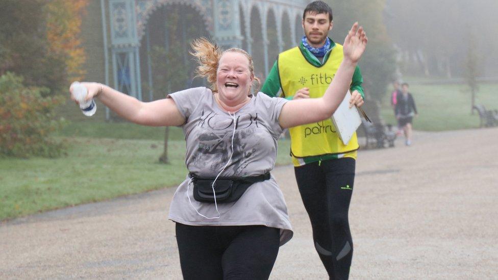 Dawn Nisbet crossing the finish line with her hands in the air and a big smile on her face