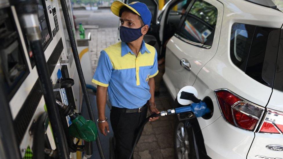 A worker fills up the tank of a car with diesel at a petrol station in New Delhi