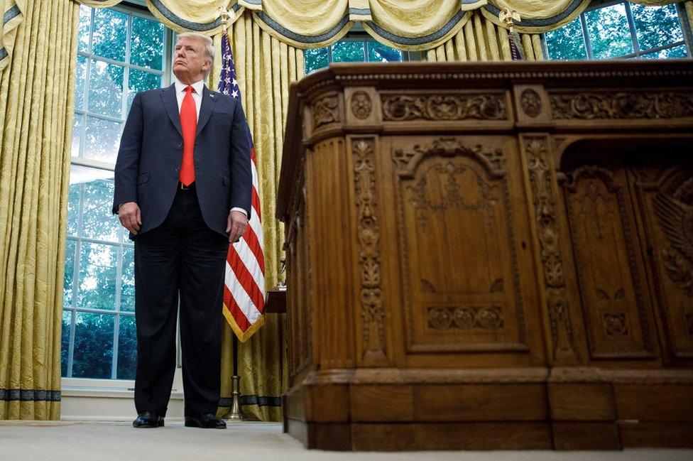 Donald Trump stands in the Oval Office