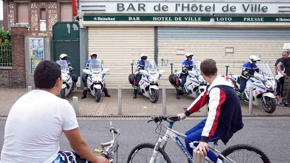 Police motorcyclists wait on pavement