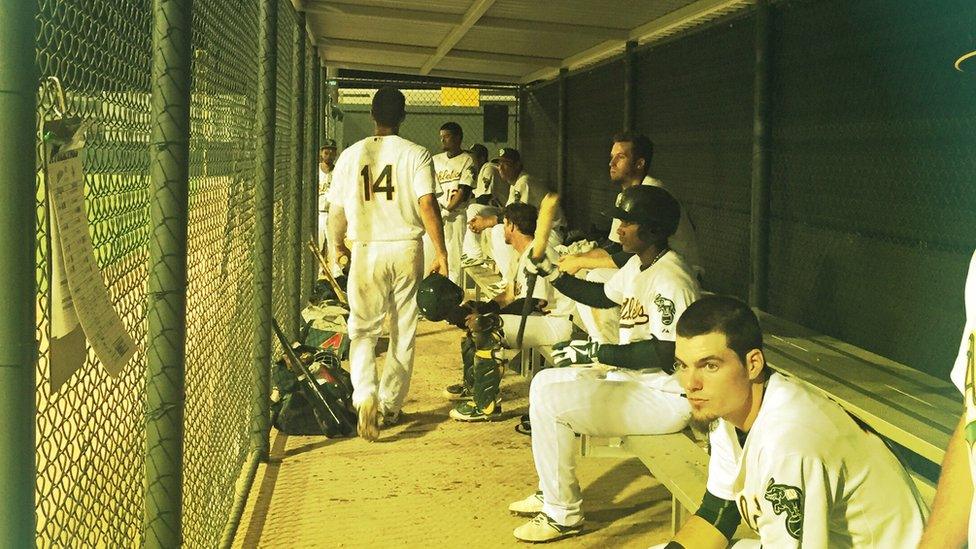 A's players watch the game from their team dugout.