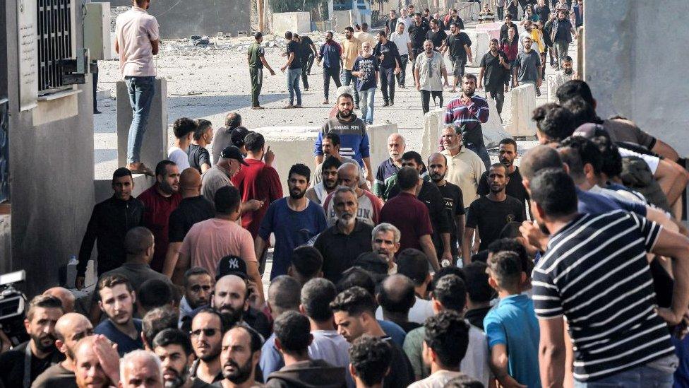 A crowd of Palestinian workers cross through the Kerem Shalom crossing