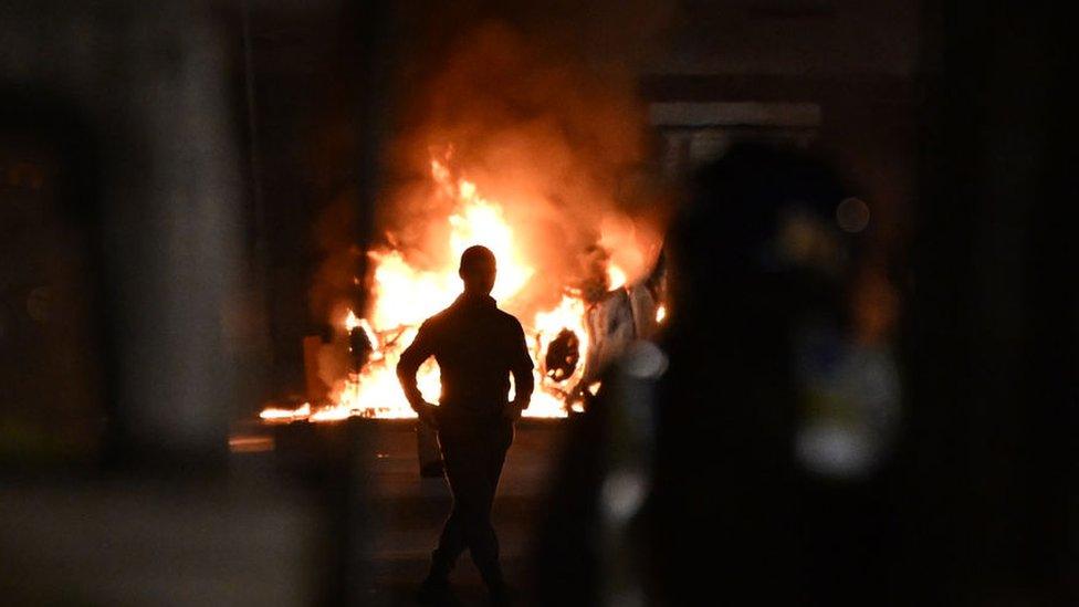 An upturned car burns at the scene of disorder in Cardiff