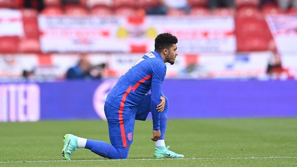 Jadon Sancho of England takes a knee in support of the Black Lives Matter movement ahead of the international friendly match between England and Romania