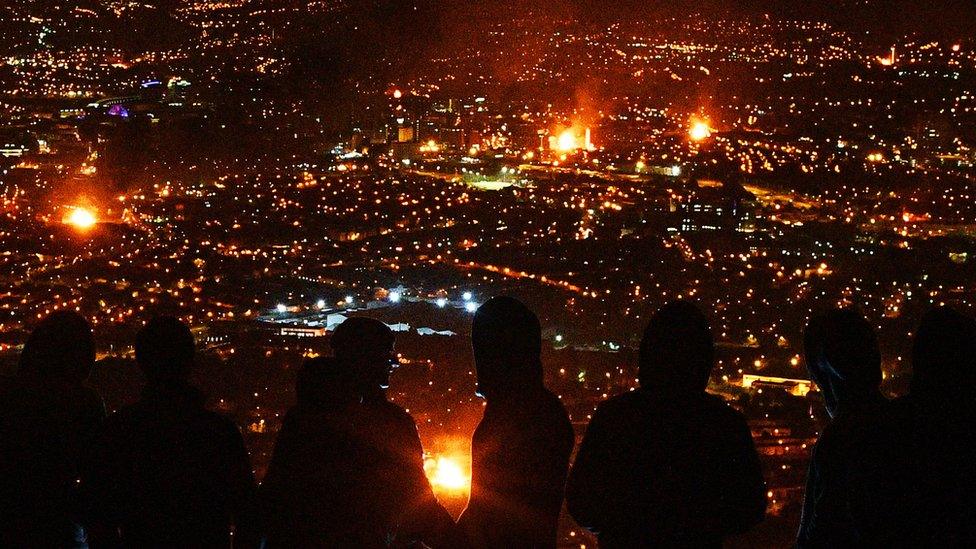 People watch bonfires across Belfast from the top of Black Mountain