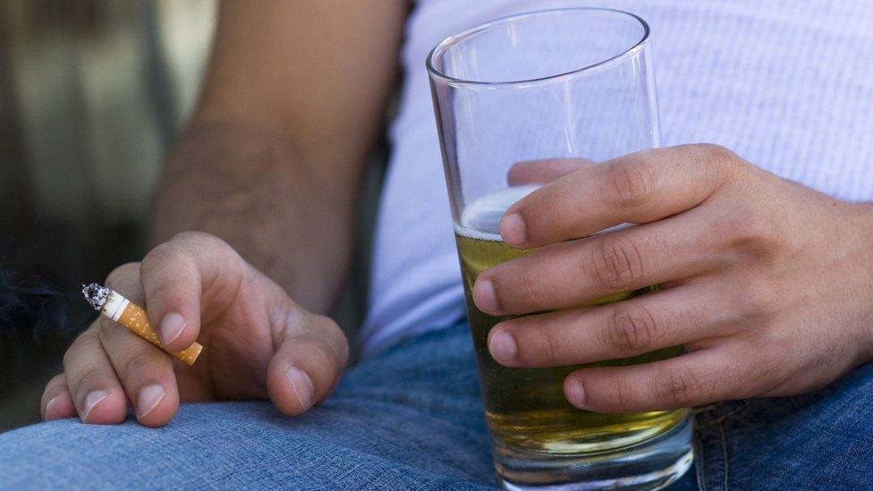 Person holding a cigarette and beer