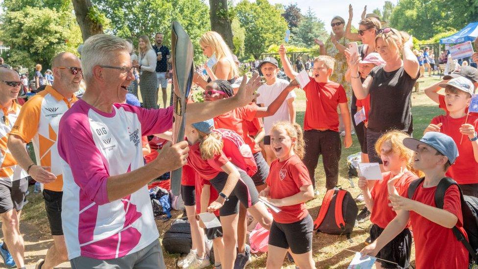 Roger Graves holding the baton to cheering children