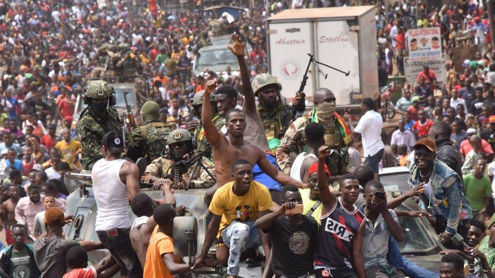 People celebrate in the streets with members of Guinea's armed forces after the arrest of Guinea's president, Alpha Conde, in a coup d'etat in Conakry, September 5, 2021.