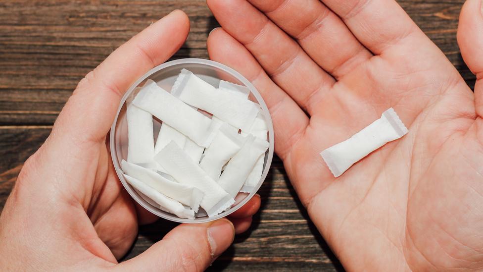 Male hands hold in hand a box of snus and nicotine pouch