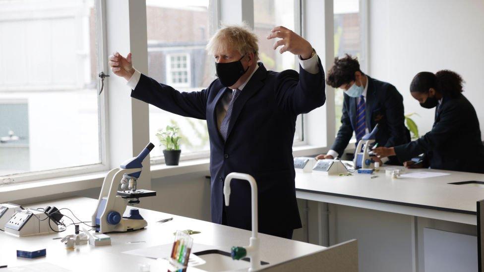 Boris Johnson at raises arms while on a visit to King Solomon Academy in Marylebone, London