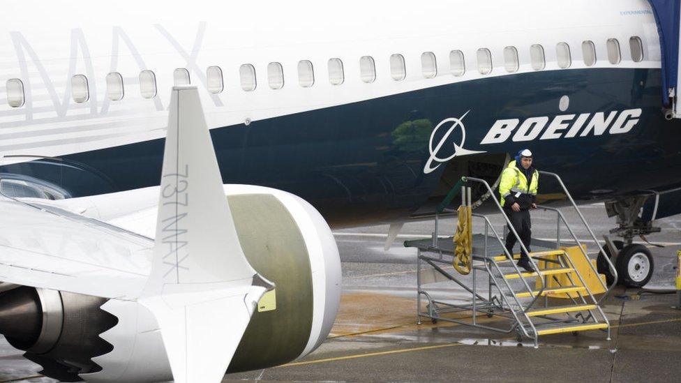 A worker stands by a Boeing 737 MAX aeroplane on the tarmac at the Boeing Renton Factory in Washington