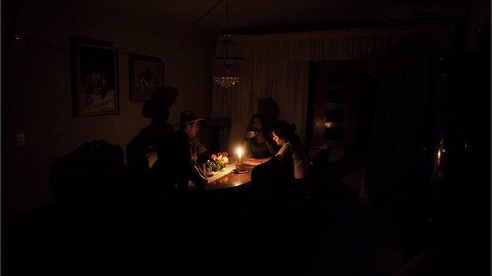 A family sit at a candle lit table in the state of Barinas, 600 km west of Caracas on April 25, 2016