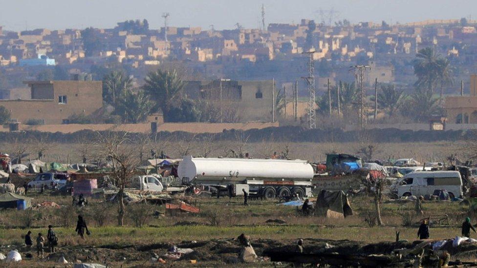 IS members walk in the last area held by the jihadist group in Baghuz, Syria (18 February 2019)