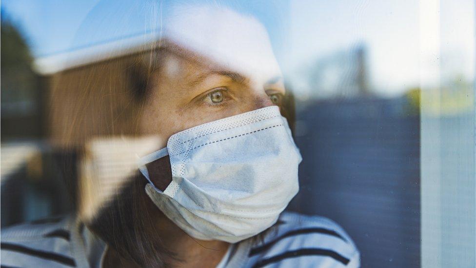 picture of someone wearing a mask looking out of the window