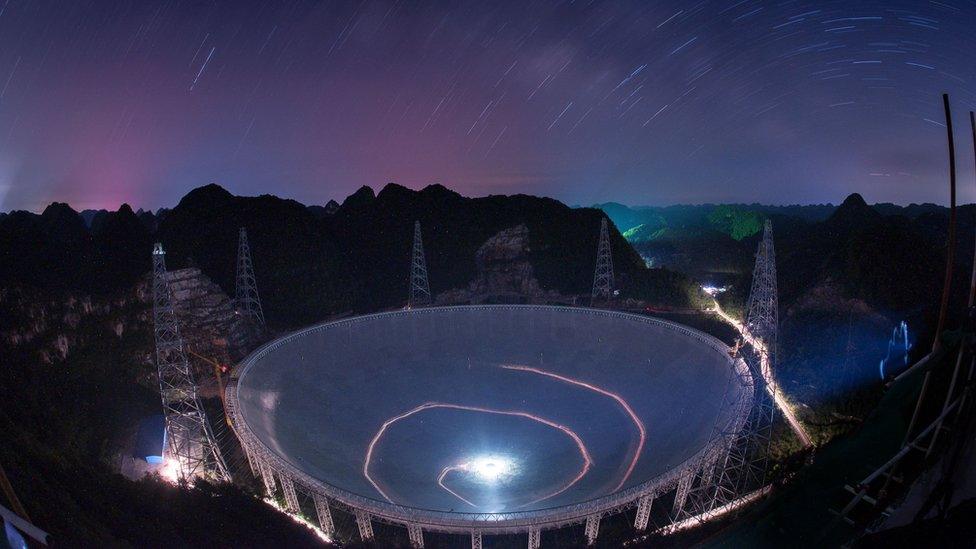 A vehicle leaves light trails in a long exposure photo as it drives beneath the Five-hundred-meter Aperture Spherical Telescope (FAST) in Pingtang County in southwestern China"s Guizhou Province Monday, June 27, 2016.