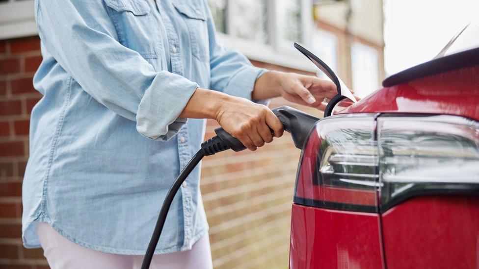 Woman charging car at home