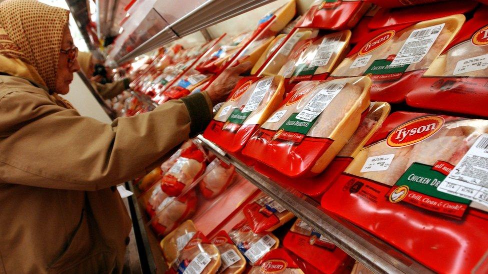 A supermarket shopper examines the chicken products produced by Tyson