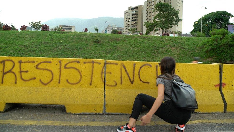 A woman hides behind barricade with the word "resistance"