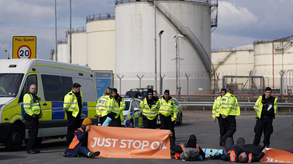 Police officers look at activists from Just Stop Oil taking part in a blockade at the Kingsbury Oil Terminal, Warwickshire