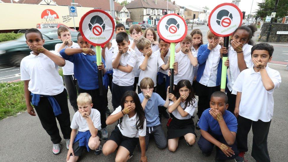 Pupils from Bowes Primary School in Enfield, north London, cover their mouths as they take part in the ClientEarth "Say No to Dirty Air" campaign outside their school, which is adjacent to the North Circular ring road.