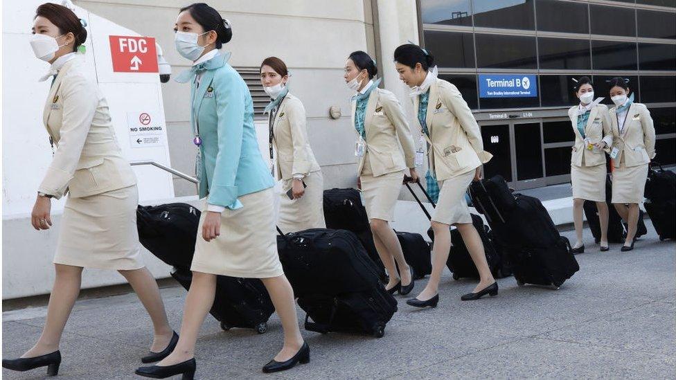 A flight crew from Korean Air, many wearing protective masks, depart the international terminal after arriving at Los Angeles International Airport (LAX) .