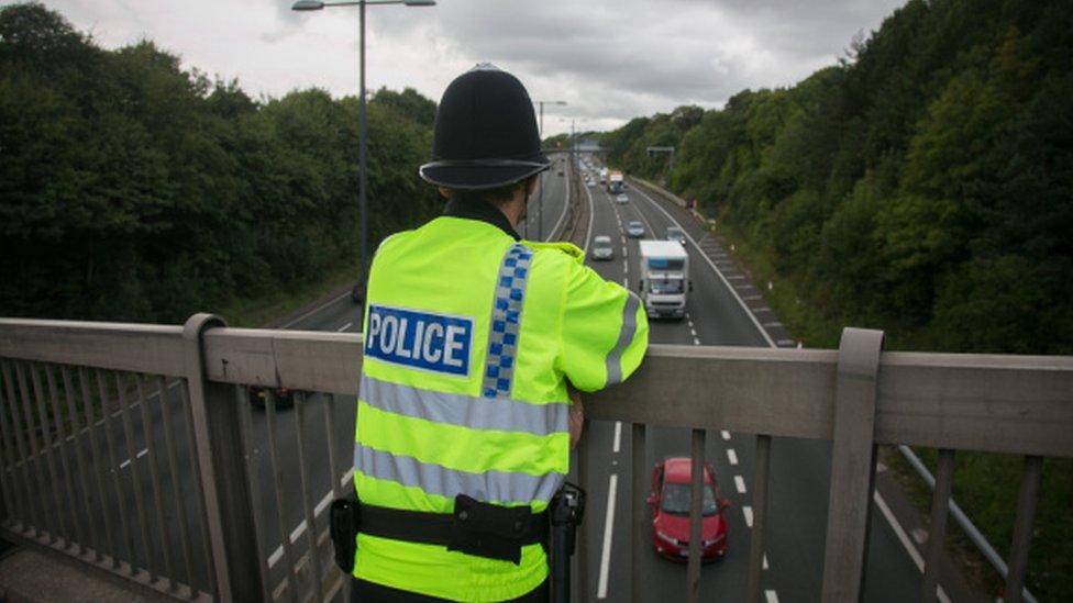 A police officer stood on a motorway bridge