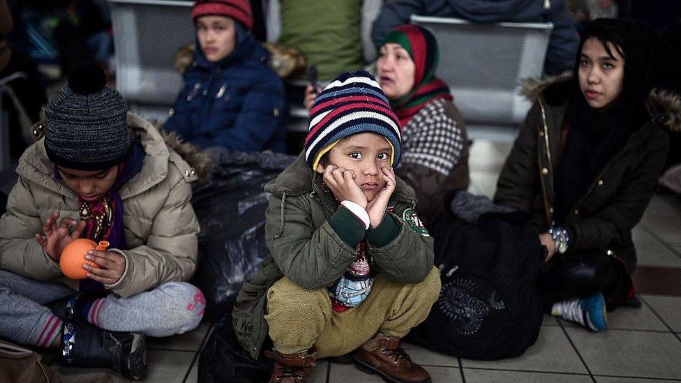 Migrants and refugees wait in the port of Piraeus, after their arrival from the islands of Lesbos and Chios on February 24, 2016.