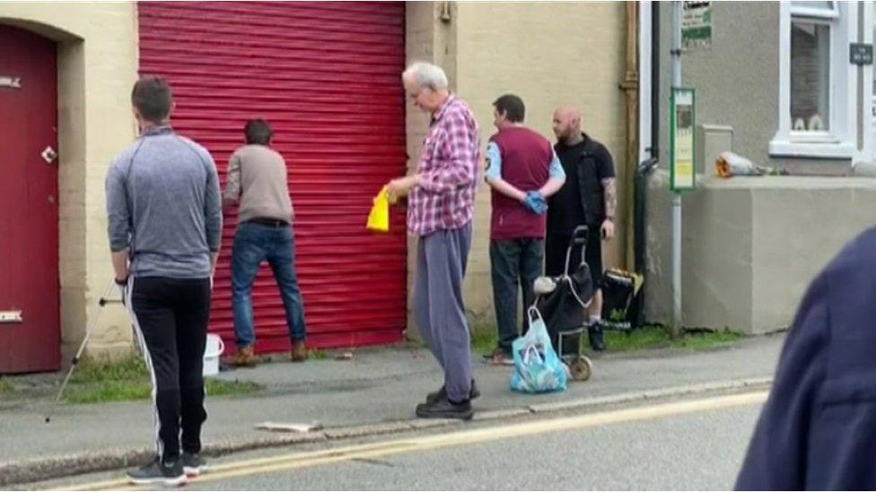 Residents in Penygroes remove a swastika from the Ogunbanwo's garage