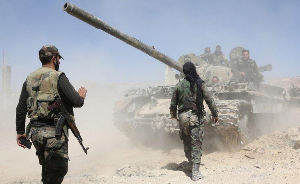 Pro-government troops on foot and riding on a tank as they advance towards the town of Douma on 7 April