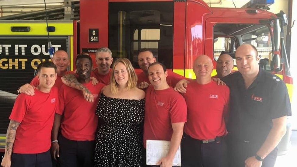 Picture of Adele with fire fighters standing in front of a fire engine